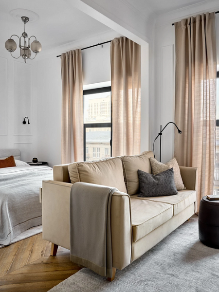 Кутовий бежевий диван Кутовий бежевий диван з подушками в мінімалістичному інтер'єрі квартири