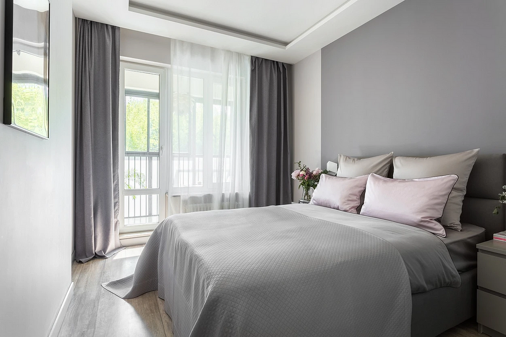 Тепло та комфорт Сіре ліжко в інтер'єрі спальні з теплими акцентами текстилю для затишку.