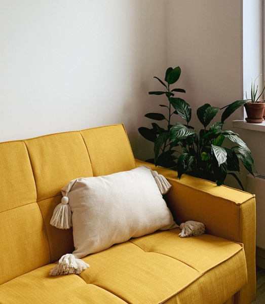 Диван біля каміну Стильний жовтий диван в вітальні з каміном і книжковими полицями.